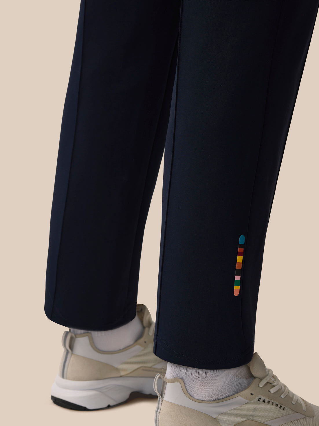 Close up of navy trousers showing the multicolor stripe detail along the outer leg near the ankle