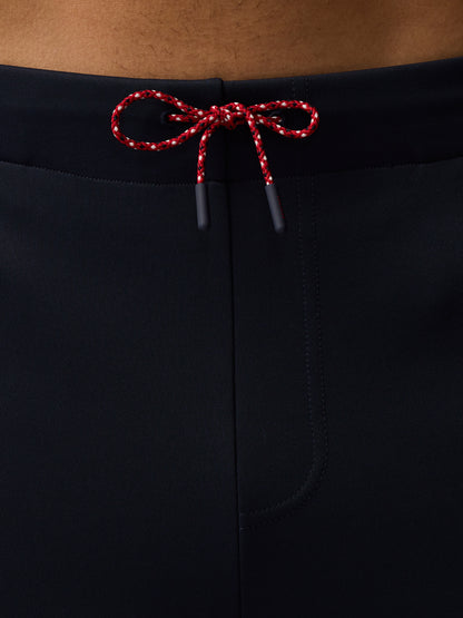 Close up of navy tailored trousers waistband with red white braided drawcords tied in a bow