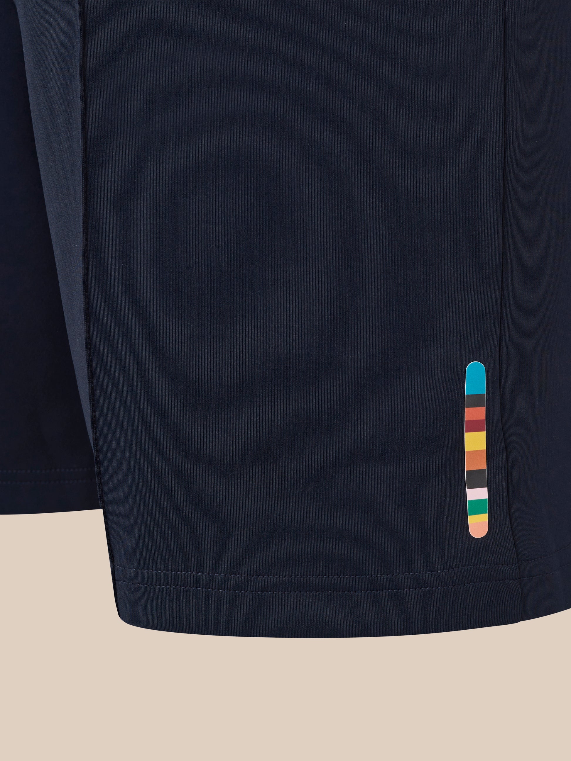 Close-up of navy England Cricket unisex shorts fabric with a colorful stripe tab