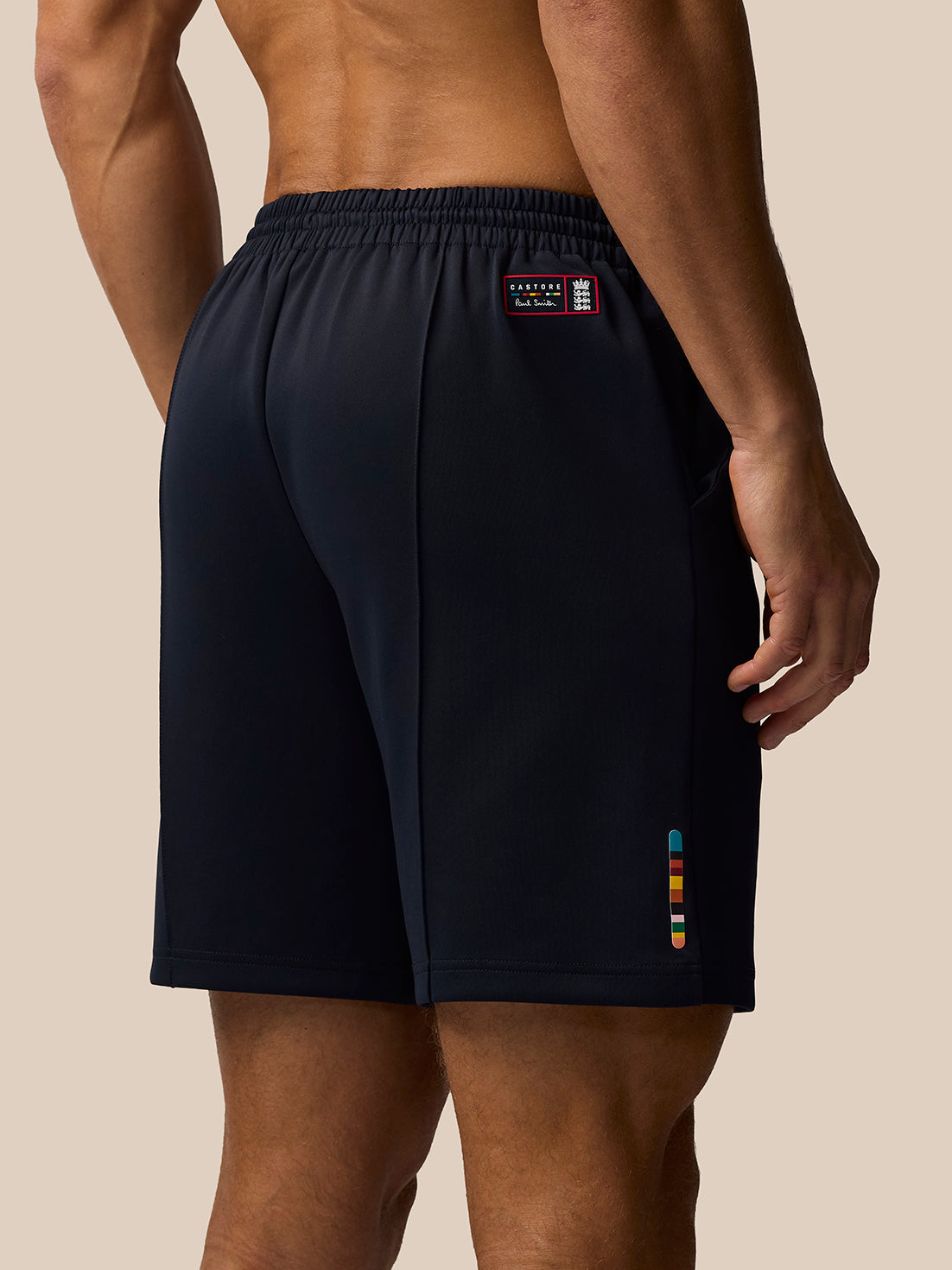 Rear view of navy England cricket shorts showing a small patch and colorful stripe at the hem