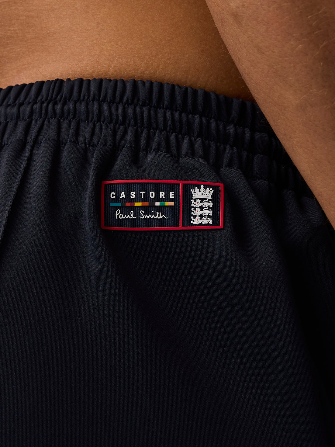 Close up of navy shorts waistband with red drawcords and ECB patch featuring Castore Paul Smith.