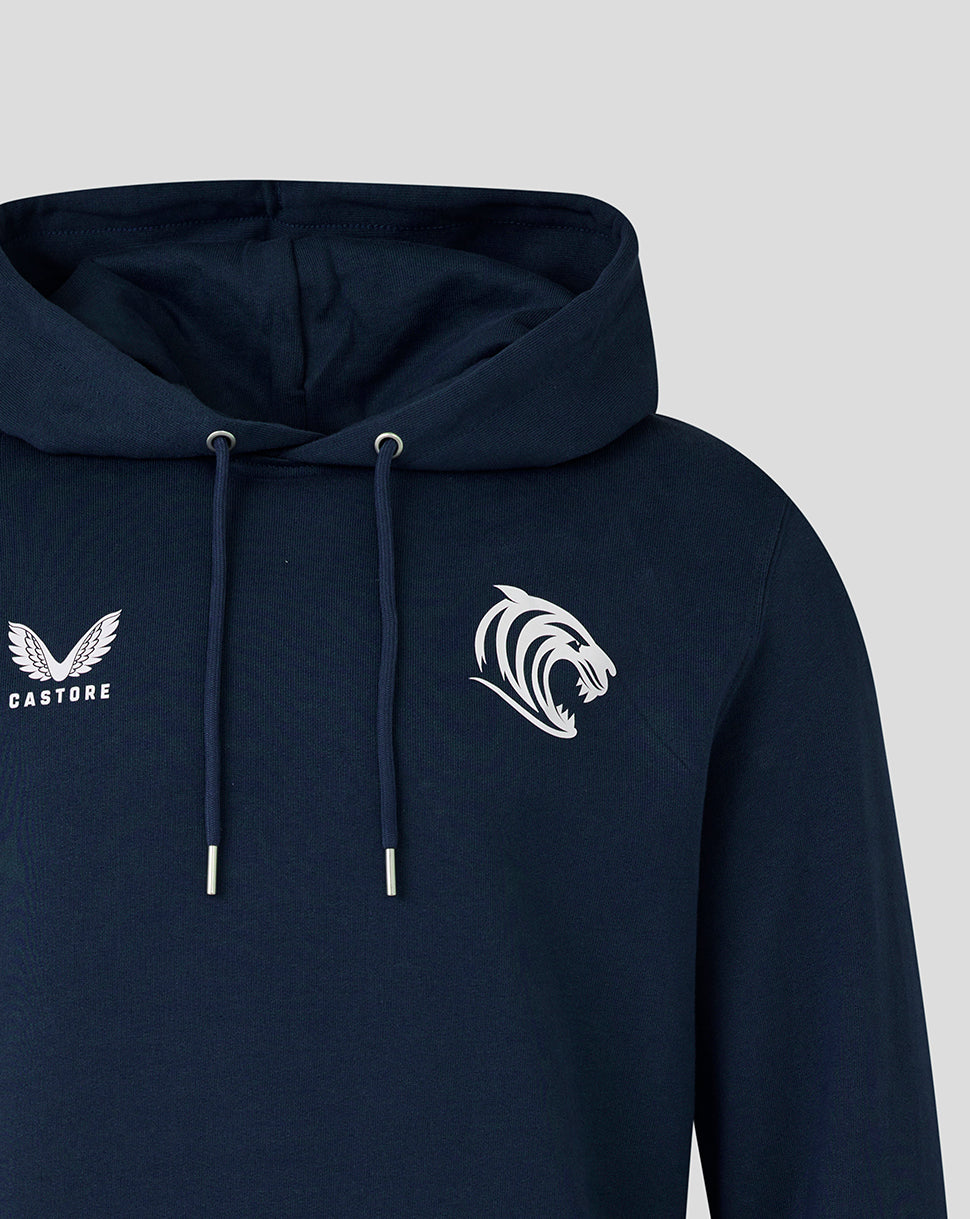 Navy hoodie close-up showing Castore logo on the left chest and tiger emblem on the right, hood and drawstrings visible.