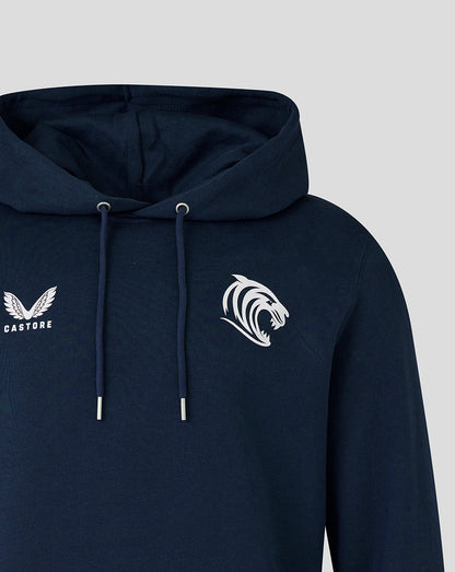 Navy hoodie close-up showing Castore logo on the left chest and tiger emblem on the right, hood and drawstrings visible.