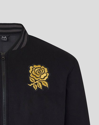 Close-up of black bomber jacket showing gold rose crest on the left chest and front zipper