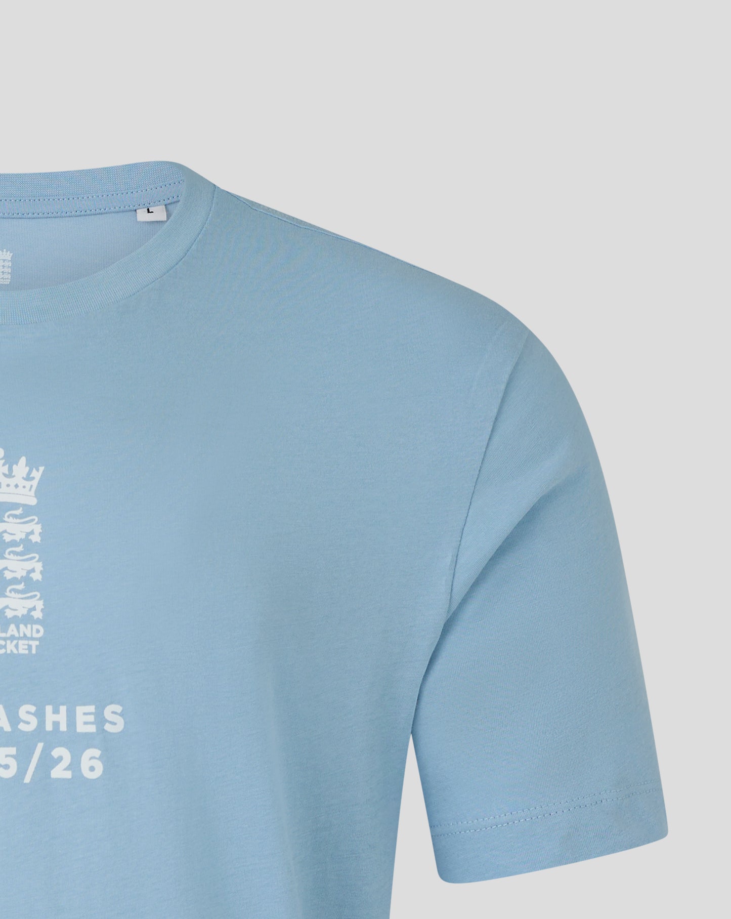 Light blue England cricket T shirt close up with crest along left chest and Ashes text.