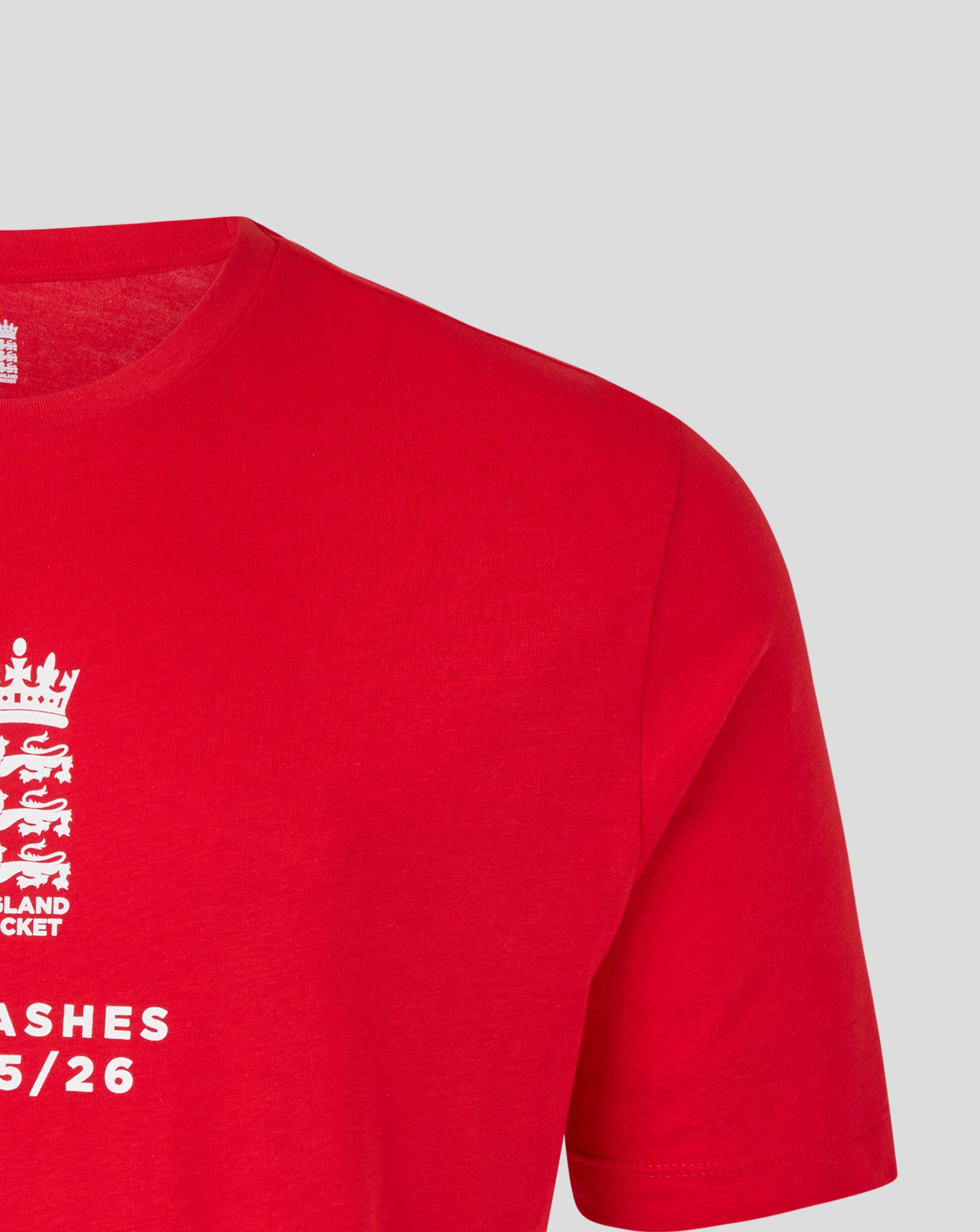 Front left chest area of red England Cricket Essentials Ashes T Shirt showing white crest and Ashes 25 26 text