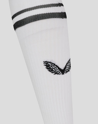 Close-up of white football sock showing black stripes at the cuff and a black emblem on the leg.