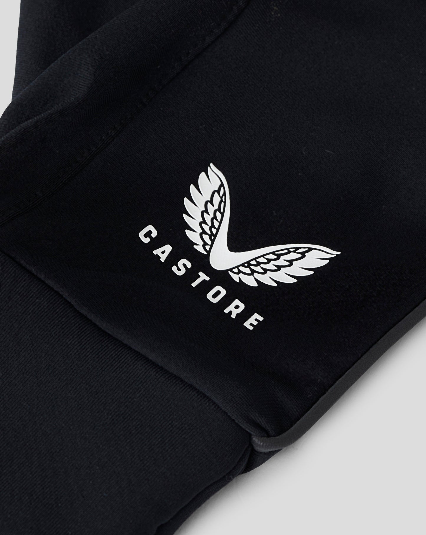 Close up of black gloves showing a white Castore wing logo on the back and a textured hex grip area