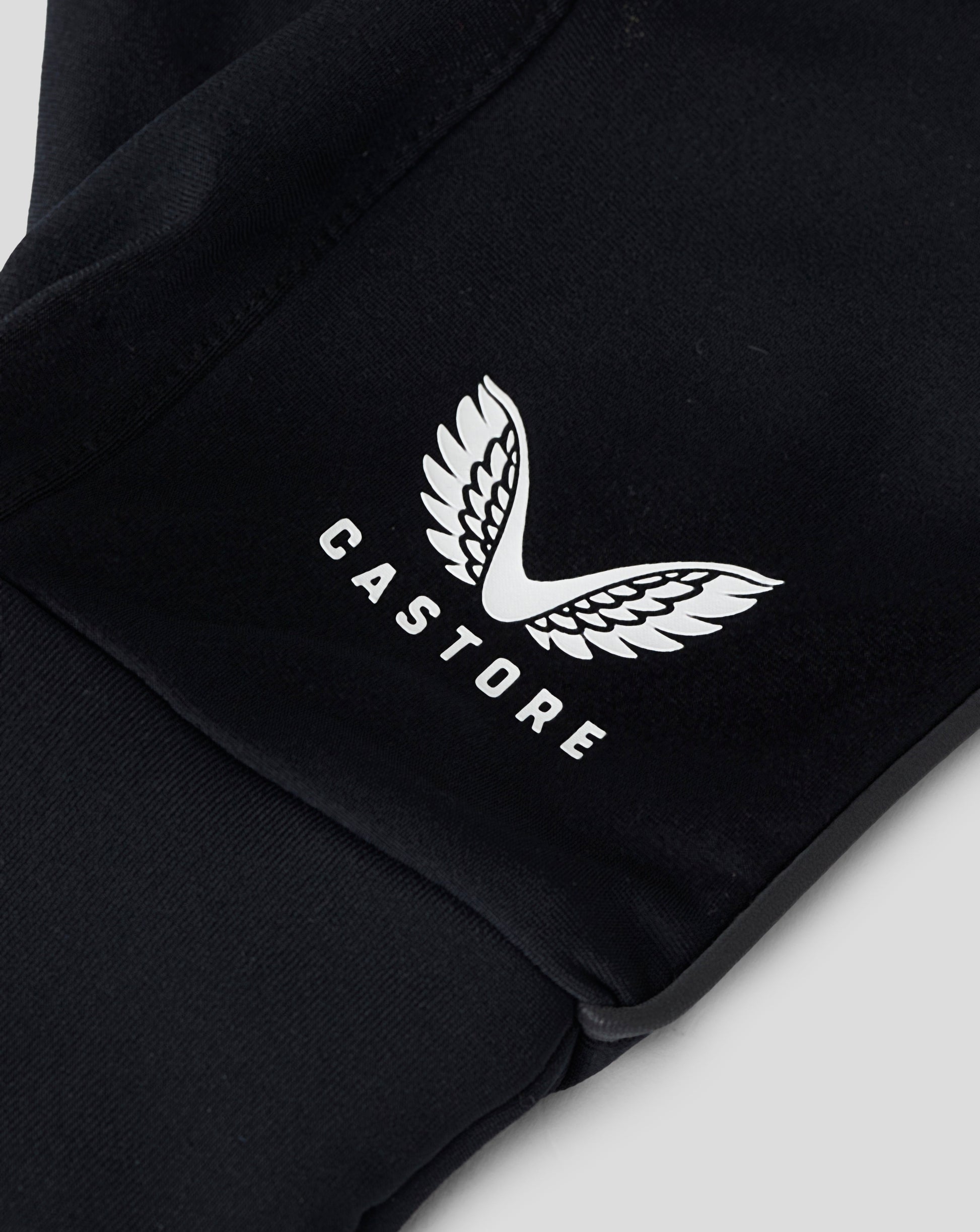 Close up of black gloves showing a white Castore wing logo on the back and a textured hex grip area