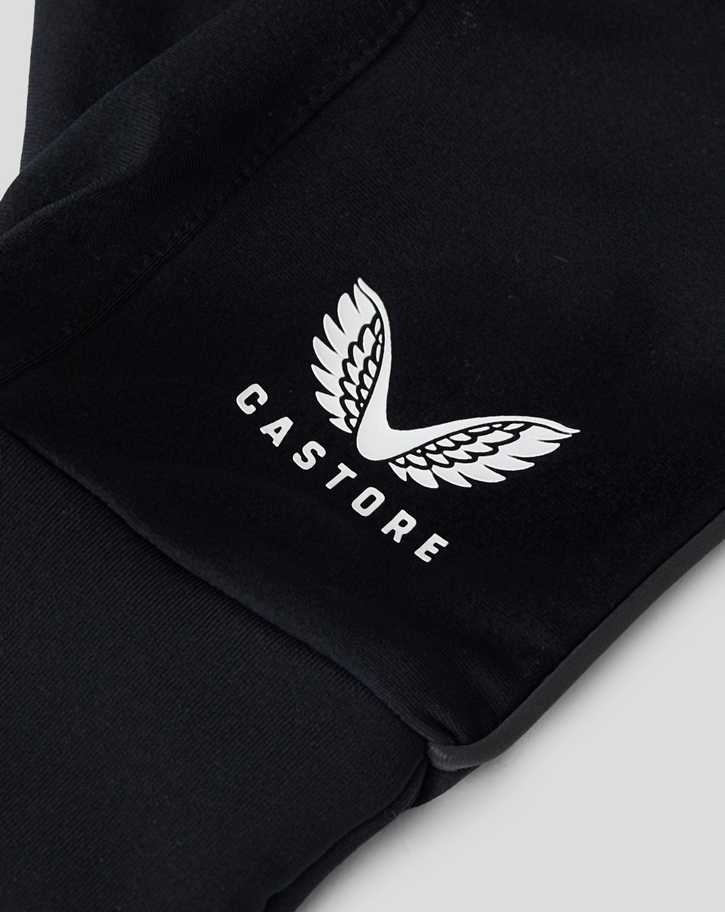 Close up of black glove material showing a white wing logo on fabric