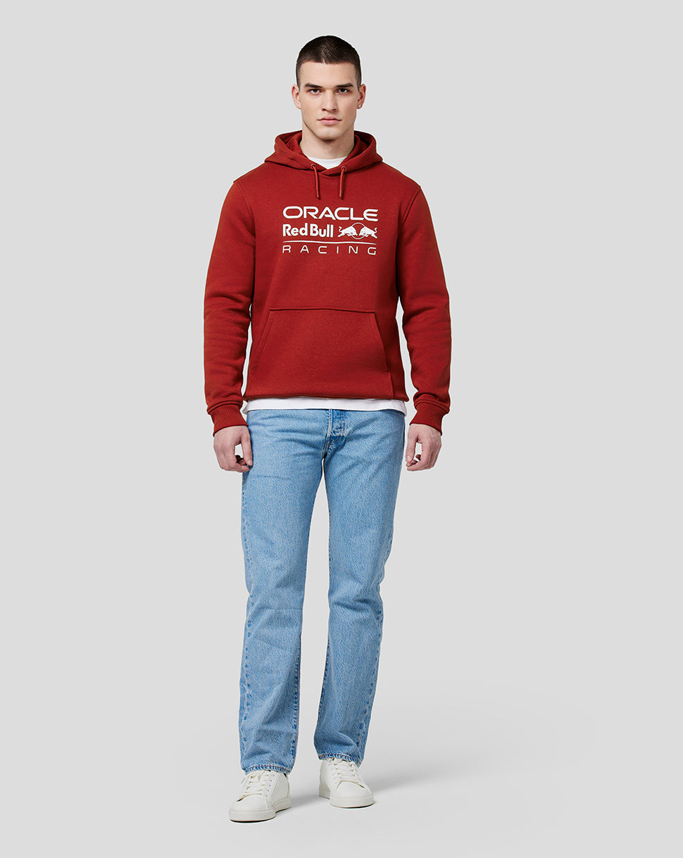 Full body shot of male model in winery red Oracle Red Bull Racing hoodie with blue jeans and white sneakers