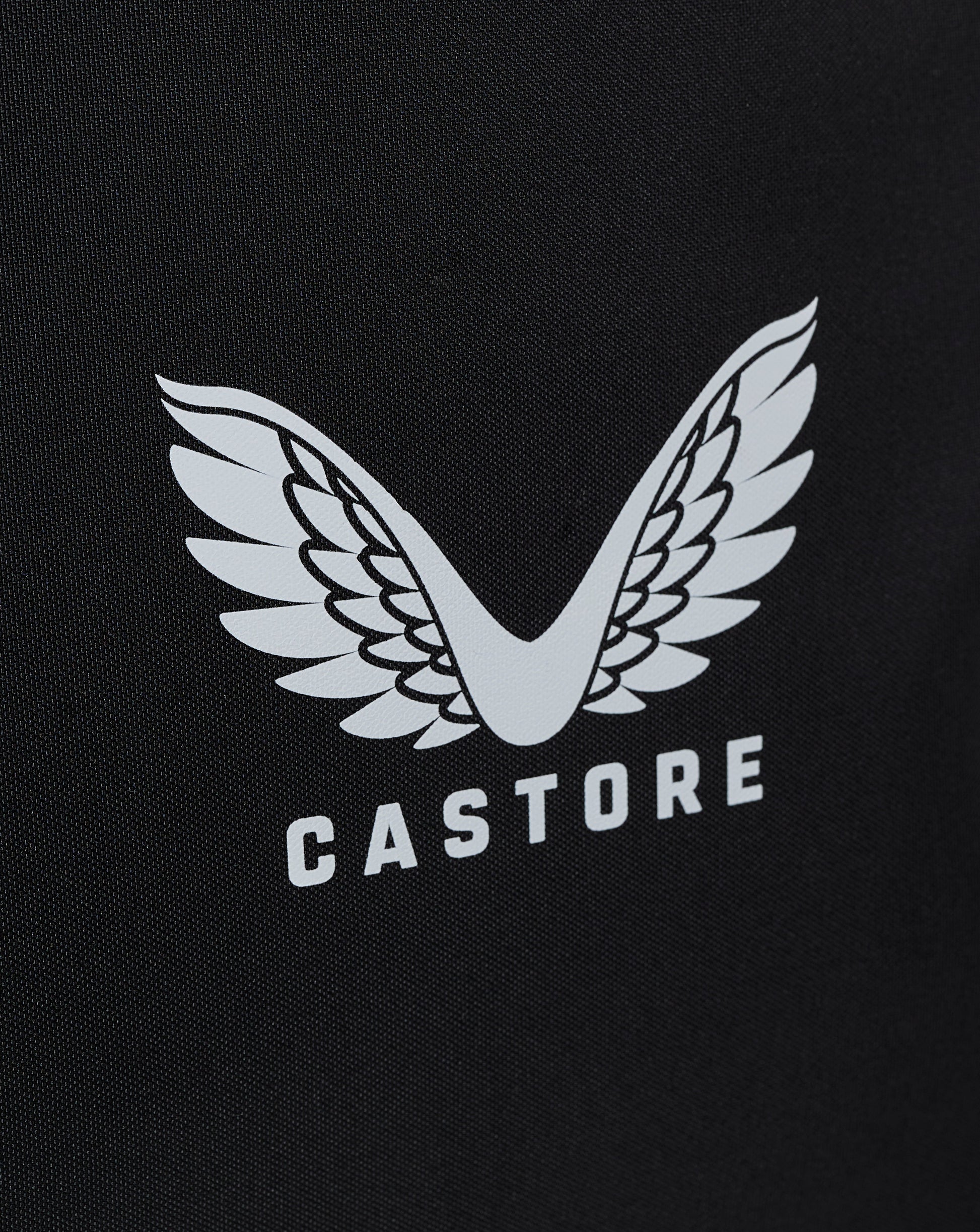 Close-up of white winged Castore logo on black bag fabric