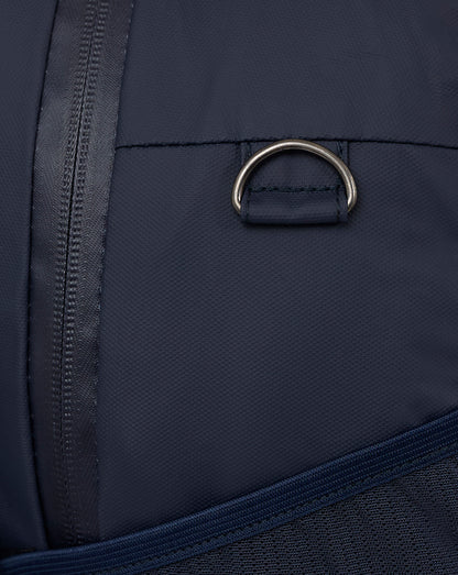 Detail of navy backpack showing a metal ring attachment and reinforced stitching.