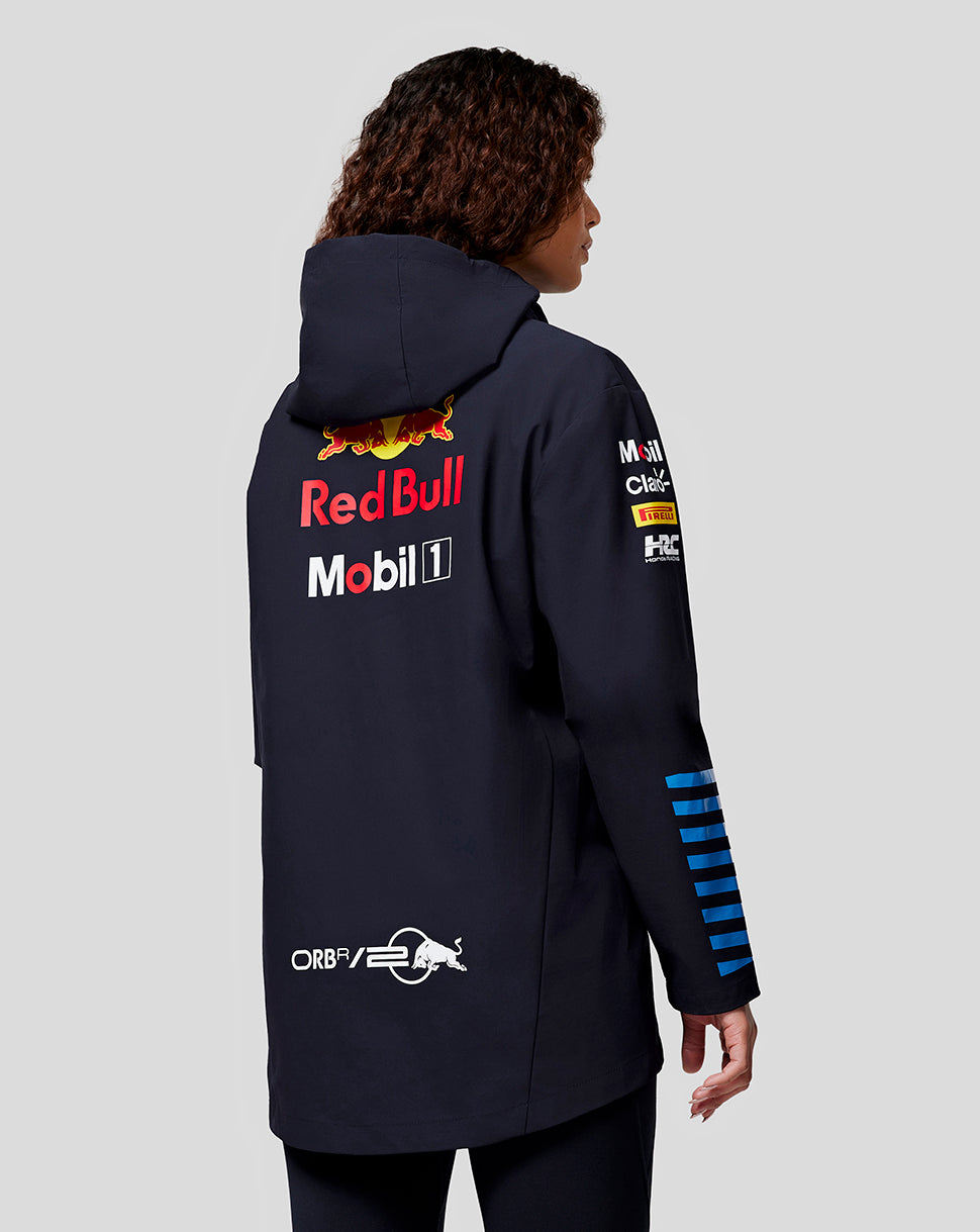 Back view of a navy Oracle Red Bull Racing jacket worn by a woman, featuring Red Bull and Mobil logos on the back and sponsor patches on the sleeve