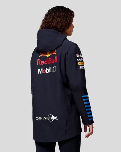 Back view of a navy Oracle Red Bull Racing jacket worn by a woman, featuring Red Bull and Mobil logos on the back and sponsor patches on the sleeve