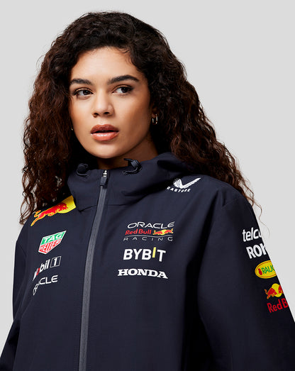 Woman wearing navy hooded water resistant jacket with Oracle Red Bull Racing logos on chest