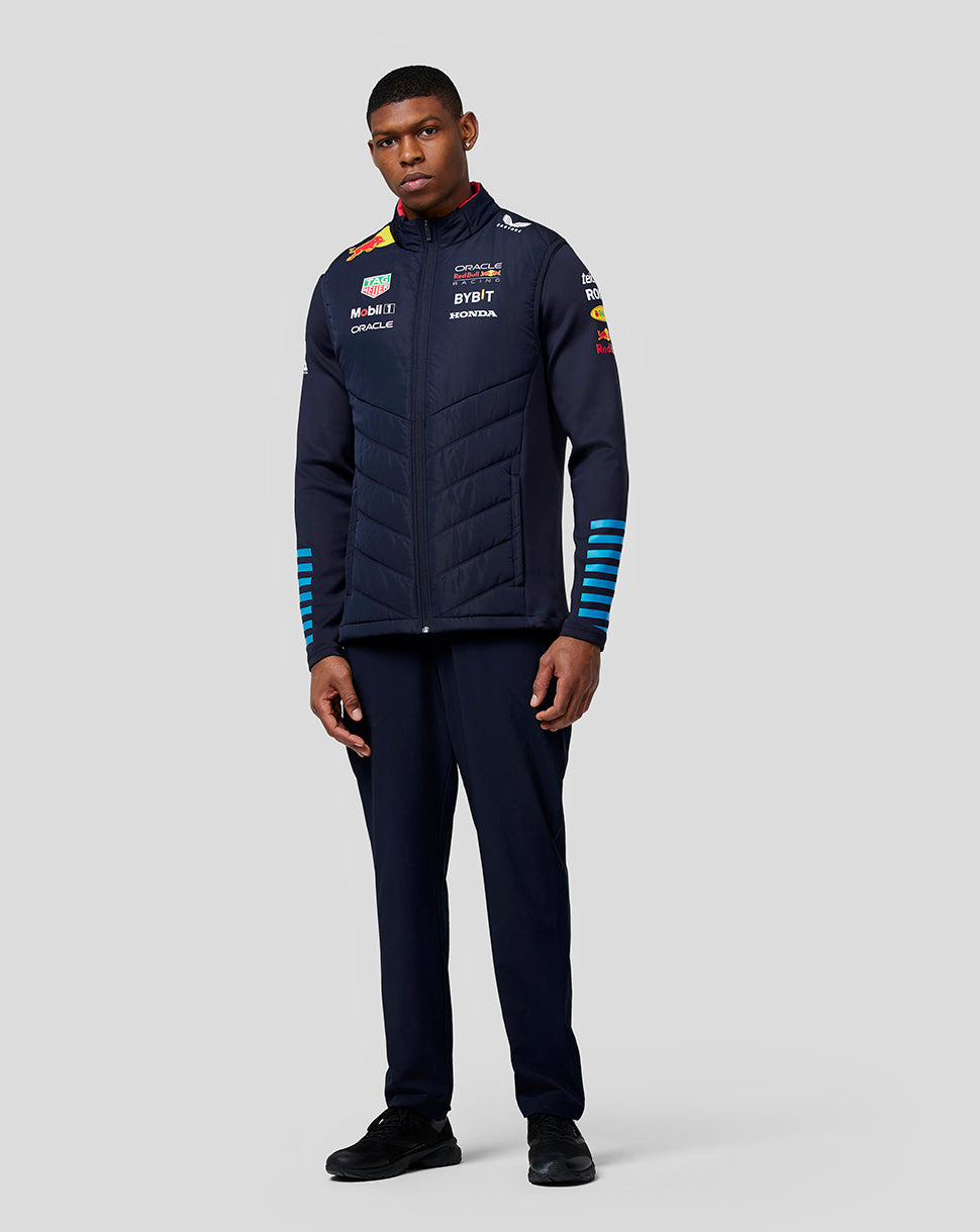 Full body shot of a man in a navy night sky teamline hybrid gilet, featuring front zip and blue striped cuffs.