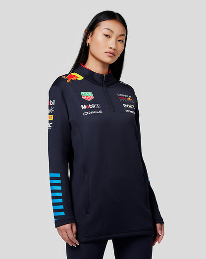 Model wearing navy Red Bull Racing Teamline midlayer with sponsor logos on chest and sleeves