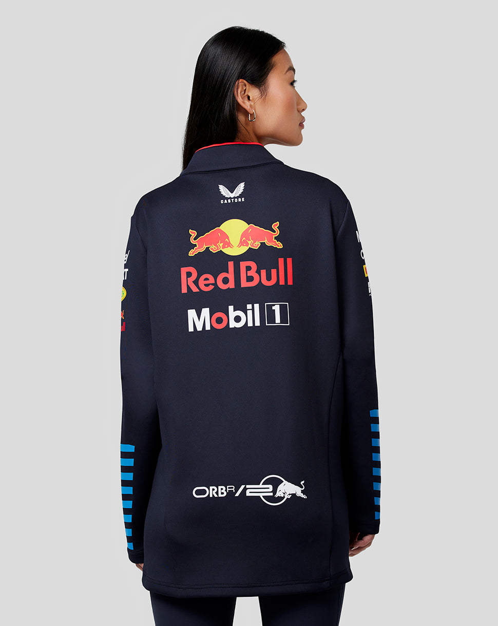 Back view of a woman wearing navy Red Bull Racing Teamline midlayer with large back graphic and blue sleeve stripes.