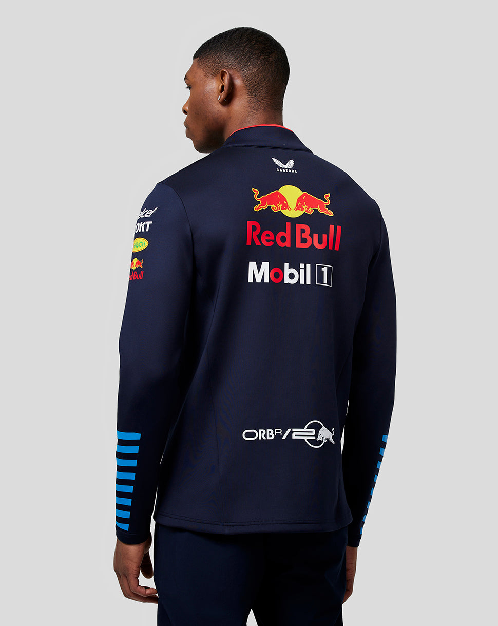 Back view of a male model wearing a navy Red Bull Racing Teamline midlayer with large back Red Bull graphic and blue sleeve stripes.
