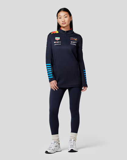 Front view of a model wearing navy Night Sky Oracle Red Bull Racing Unisex 1/4 Zip Midlayer with funnel neck side pockets and sponsor logos on chest and sleeves with blue striped cuffs