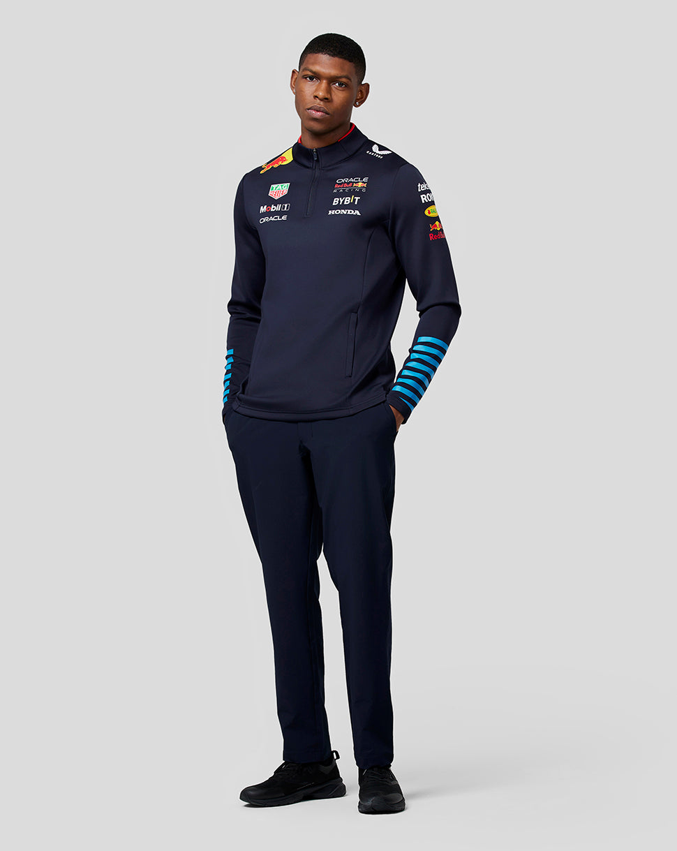 Front view of a male model wearing navy Red Bull Racing Teamline midlayer with quarter zip and sponsor logos on chest.