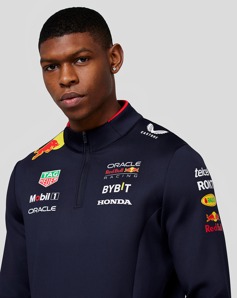 Back view of a navy Red Bull Racing midlayer on a model with a large Red Bull graphic on the back and Castore branding near the neck