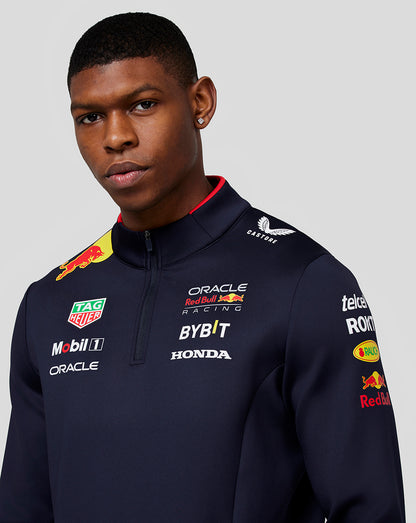 Back view of a navy Red Bull Racing midlayer on a model with a large Red Bull graphic on the back and Castore branding near the neck