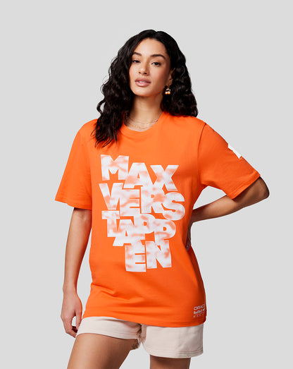 Female model in bright orange Max Expression T shirt with large white Max Verstappen graphic on the front and beige shorts.