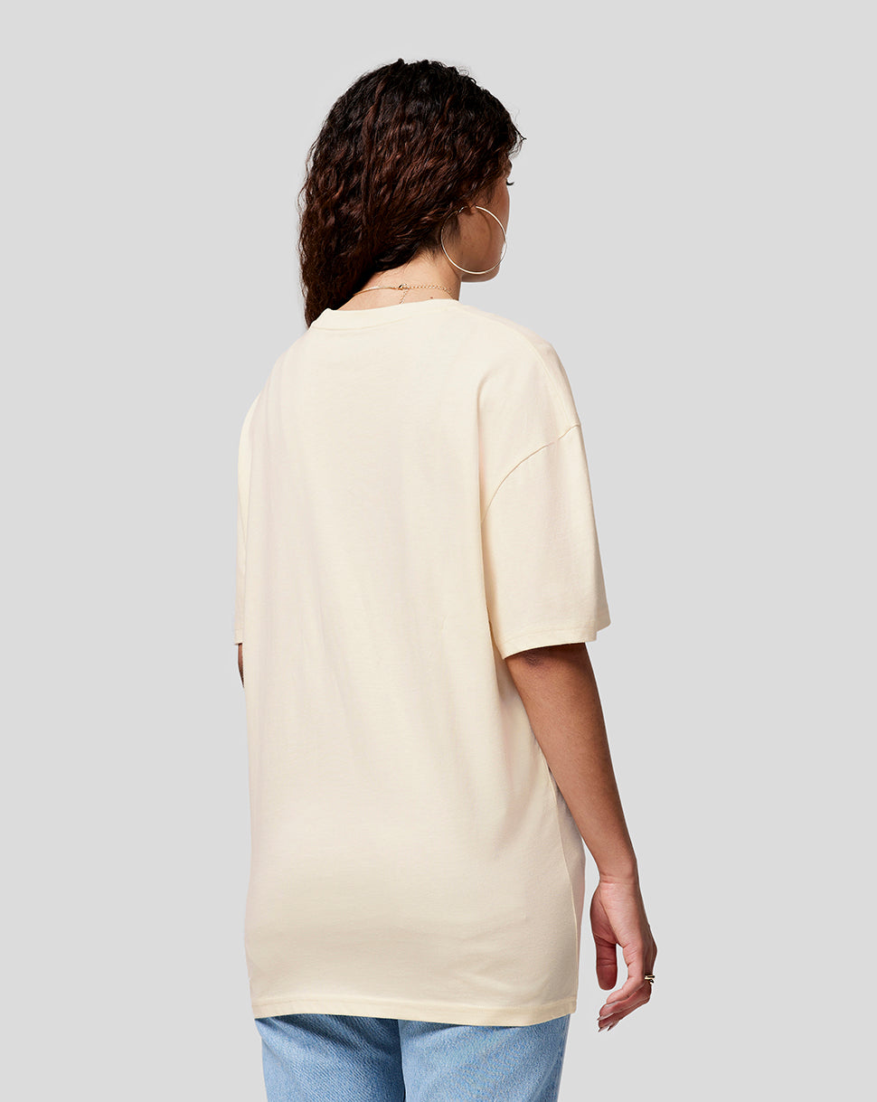 Rear view of a woman with curly hair wearing a cream oversized T shirt and hoop earrings.