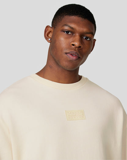 Close-up of a male model wearing an ecru Oracle Red Bull Racing oversized crew neck sweatshirt with a chest patch