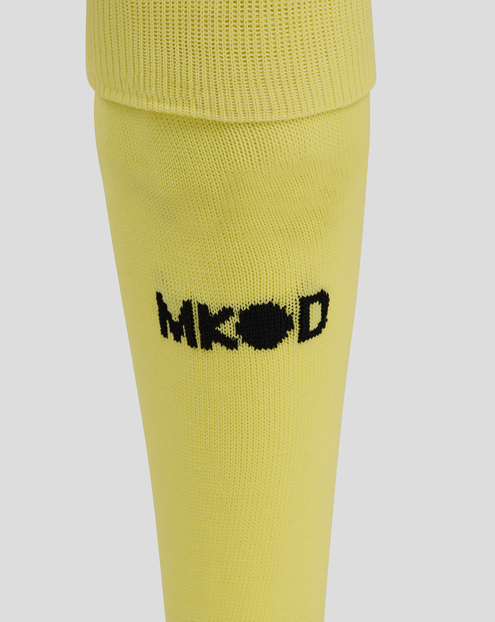 Close-up of the yellow Mk Dons goalkeeper sock with a black embroidered logo on the calf.