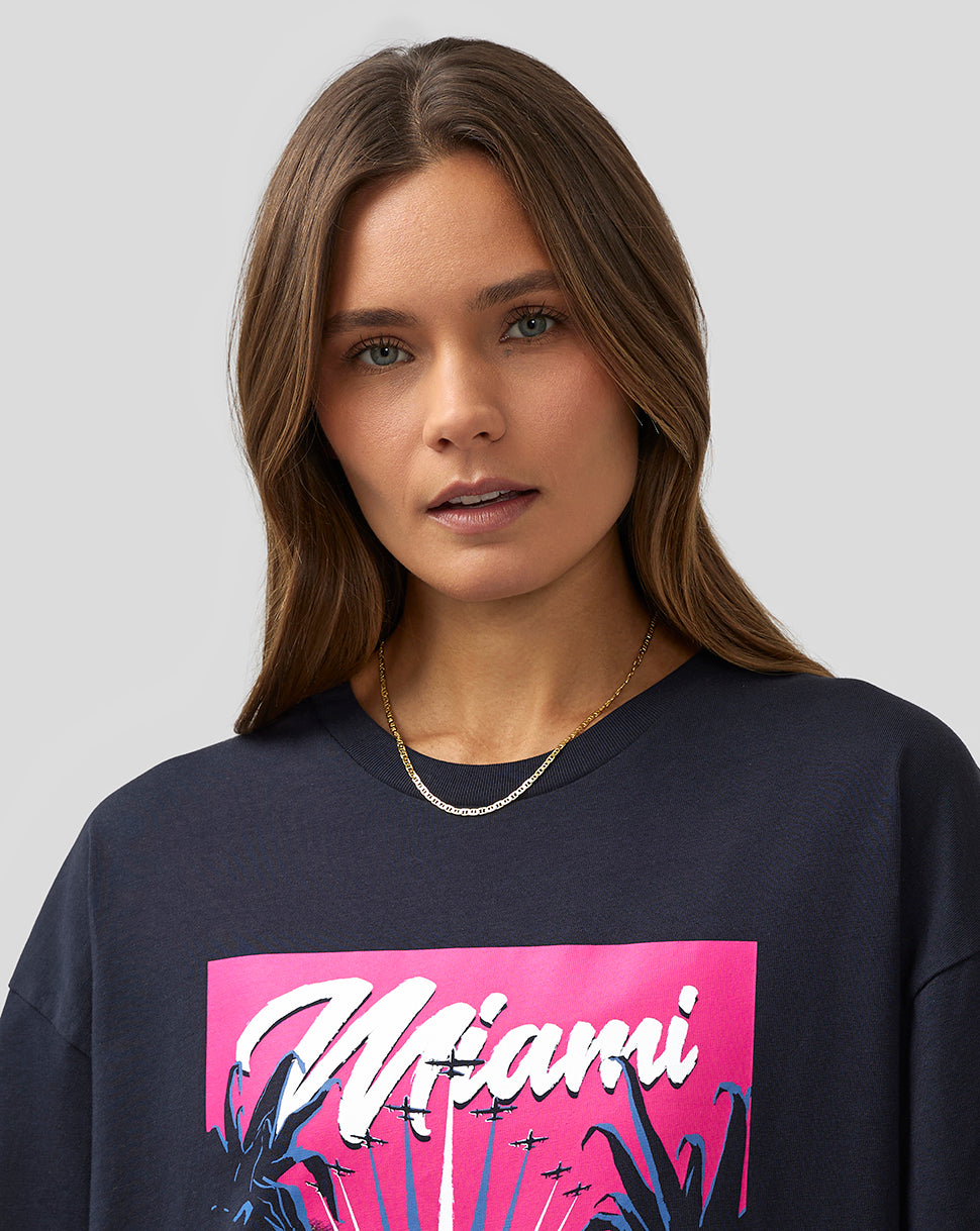Close up of a female model wearing a navy Miami graphic T shirt with a pink artwork panel.