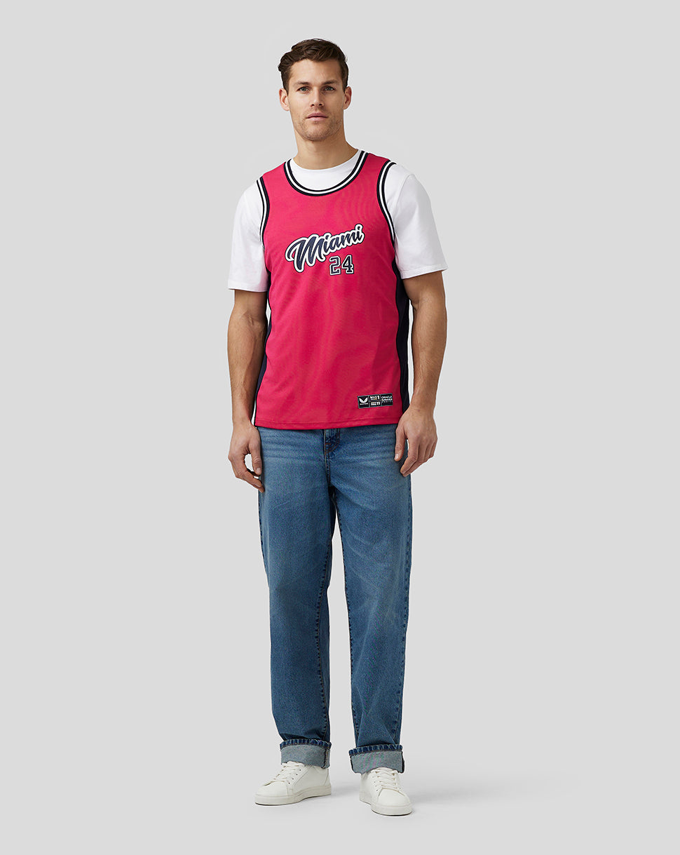 Man wearing bright pink Miami basketball jersey with white sleeves and Miami 24 on the chest