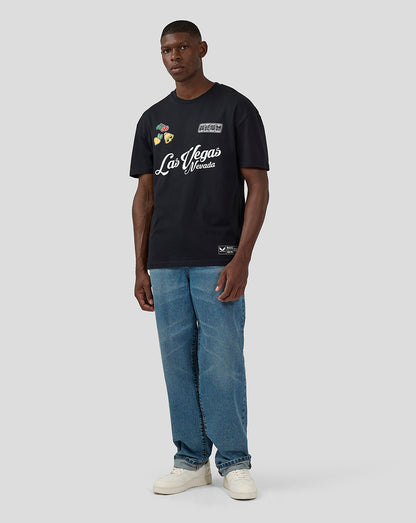 Full body shot of a man in a black Oracle Red Bull Racing Las Vegas T Shirt with blue jeans and white sneakers.