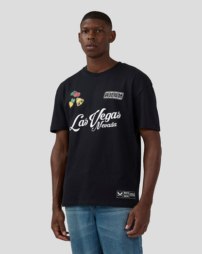 Full front view of a man wearing a black Las Vegas T shirt featuring Las Vegas script and colorful fruit motifs.
