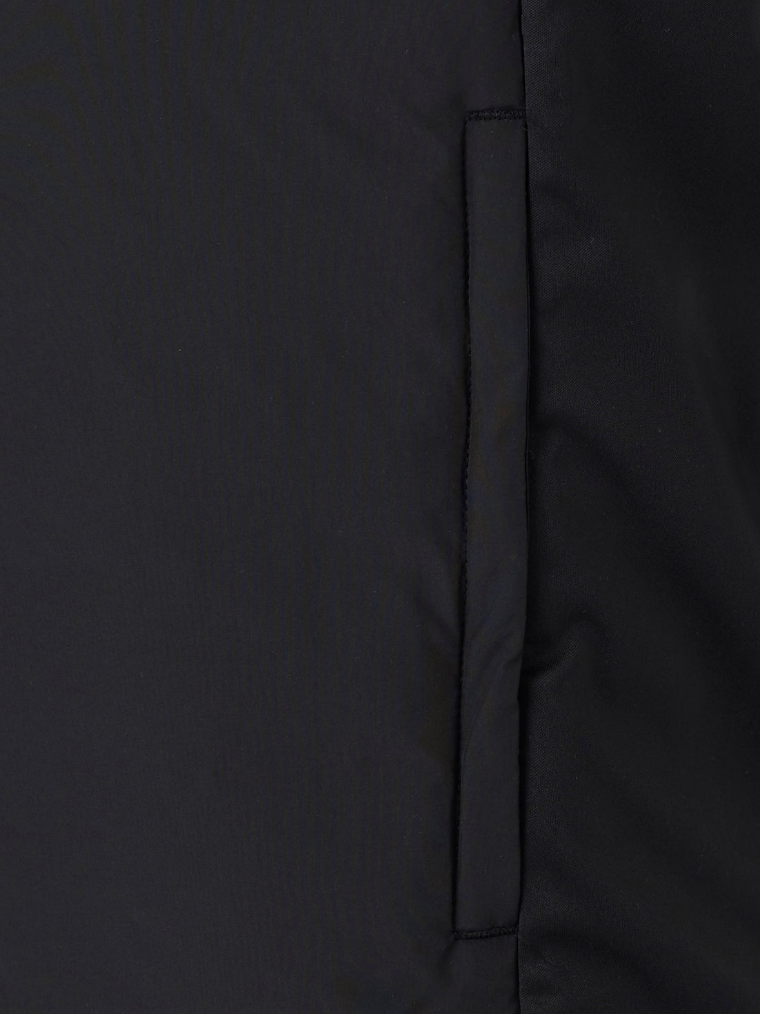 Close-up of the vertical side pocket seam on a black padded gilet