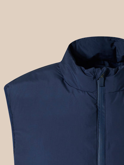 Close-up of navy padded gilet neckline with high collar and zipper