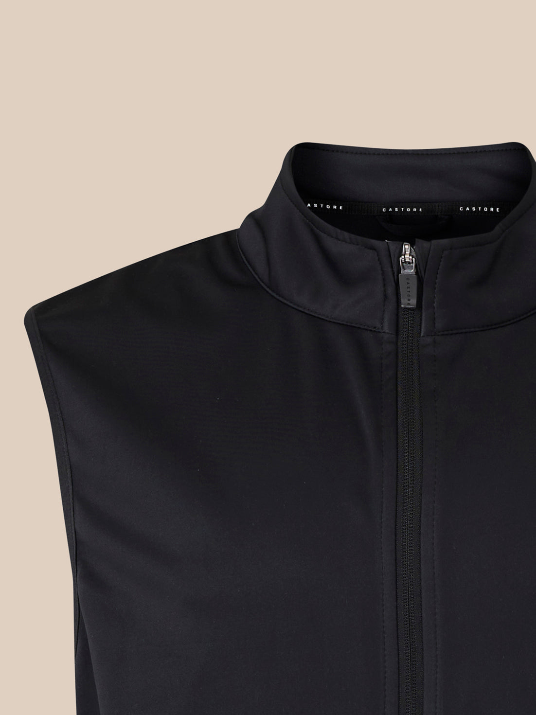 Close-up of black softshell gilet collar and front zip with Castore branding along the inner neckline.