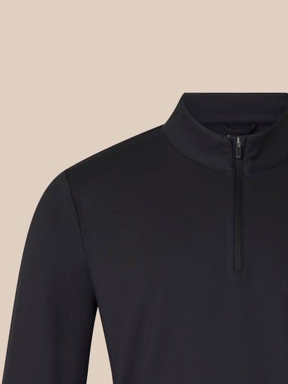 Close-up of black unisex 1/4 zip top showing the high collar and front zipper against a beige background.