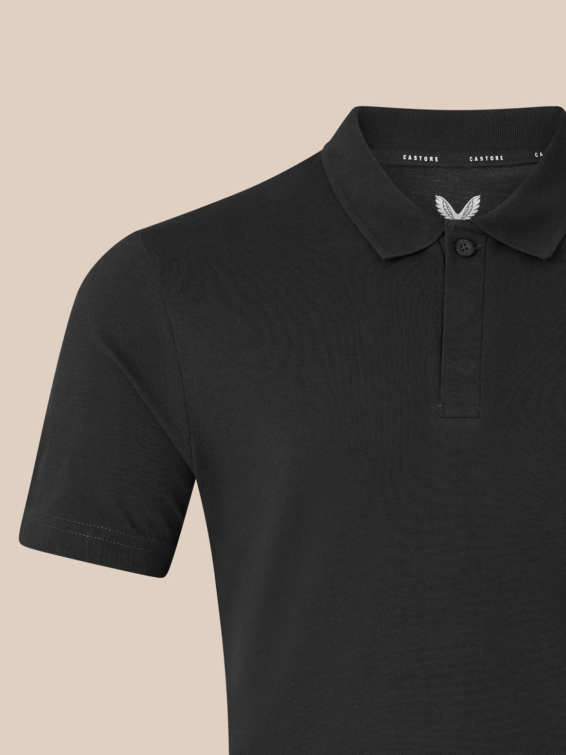 Close-up of black unisex polo showing ribbed collar and chest embroidery with the Castore logo