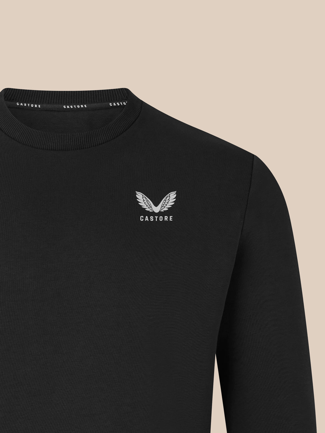 Close up of white Castore wing logo on the left chest of a black crewneck sweatshirt