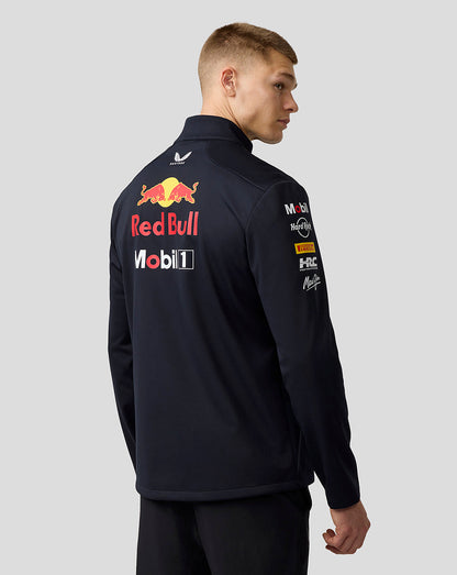 Rear three-quarter view of male model wearing navy Red Bull Racing Teamline Jacket with large logo on back.
