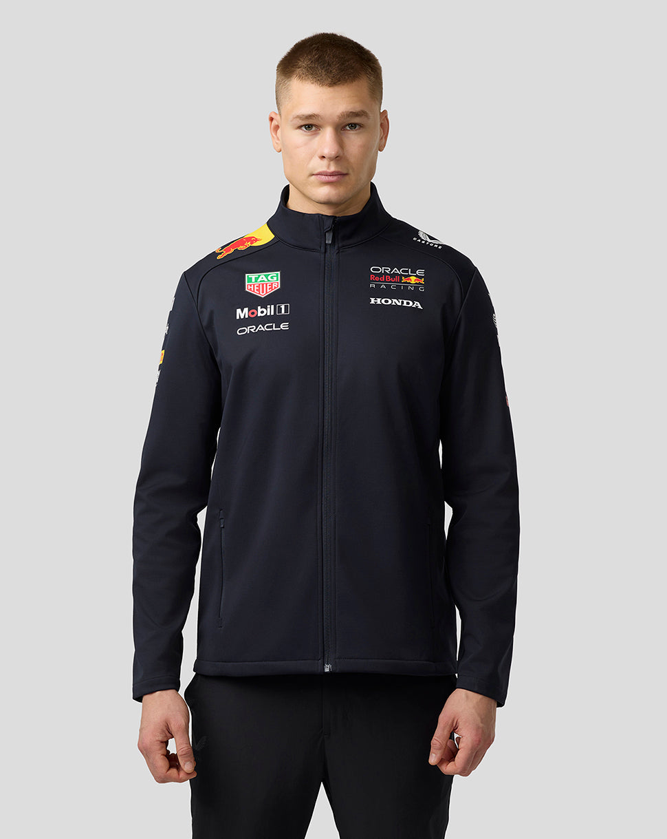 Front view of male model wearing navy Oracle Red Bull Racing Teamline Soft Shell Jacket with chest logos.