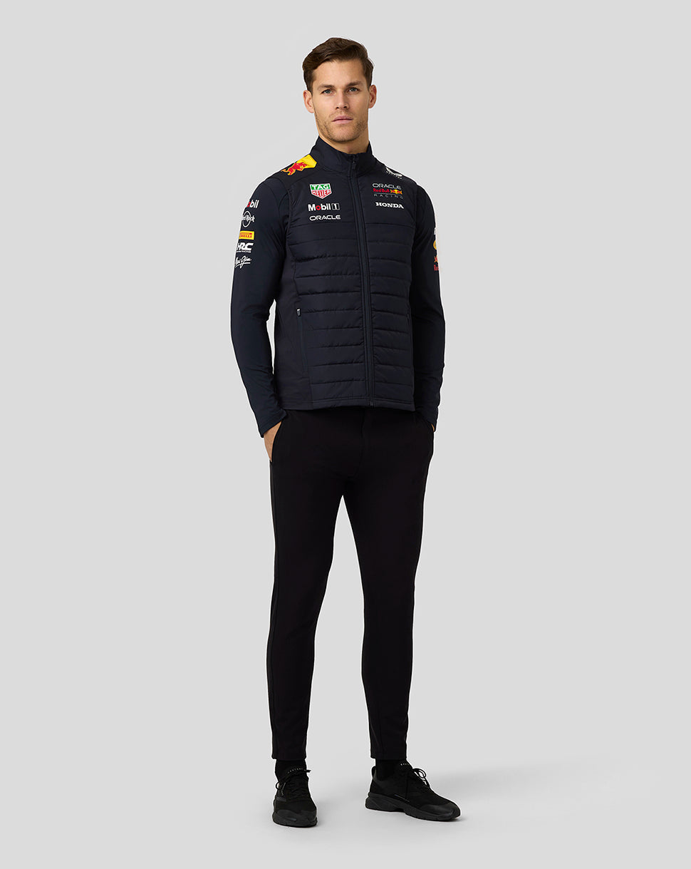 Full body front view of model in navy padded jacket with team branding and sponsor logos