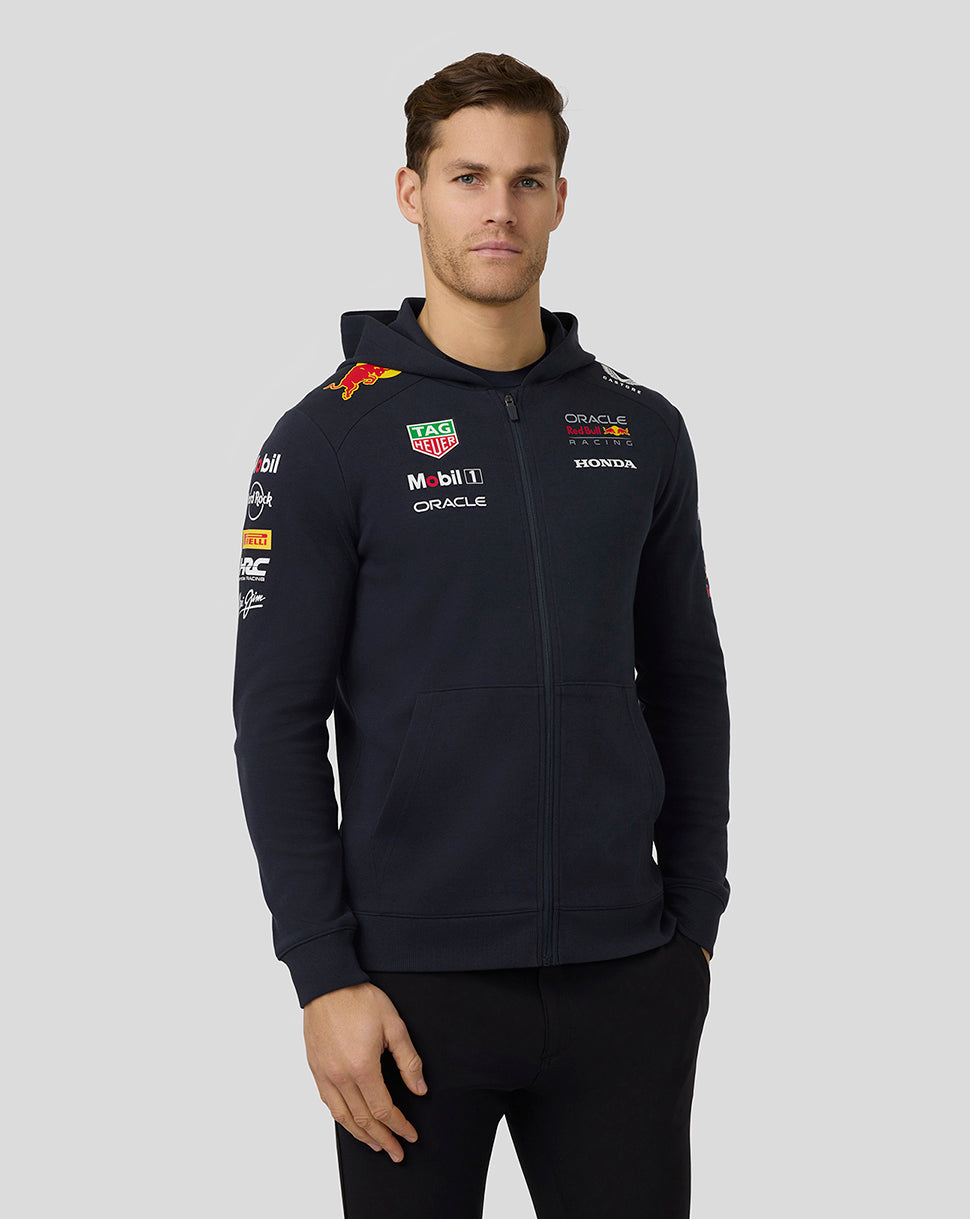 Front view of male model wearing navy Teamline Full Zip Hoodie with hood down and prominent team logos