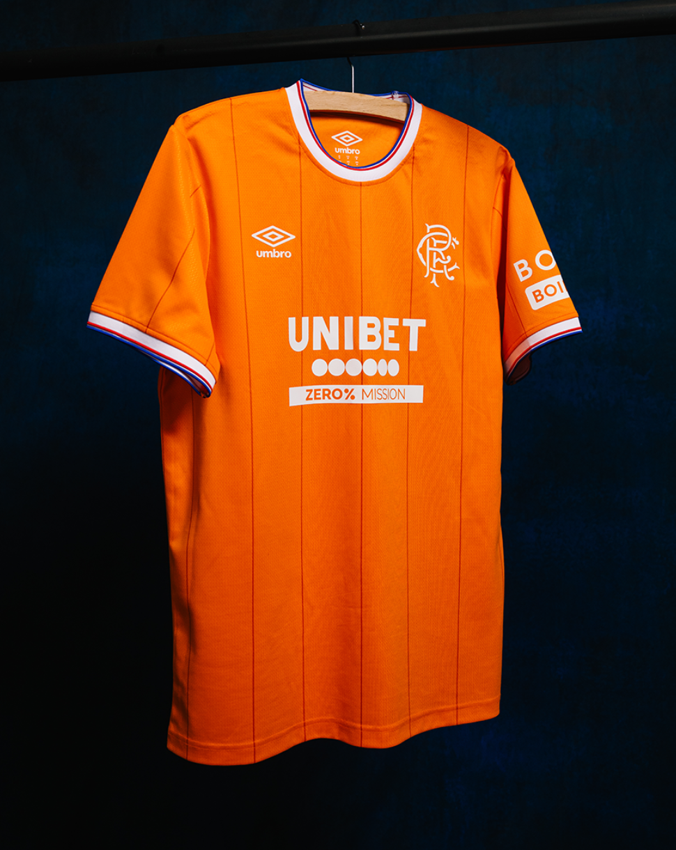 Front view of orange Rangers fourth shirt on a hanger with UNIBET sponsor, club crest on the left chest and Umbro logo on the right.