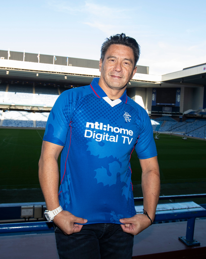 Man wearing blue Rangers retro 2002-03 home shirt in a stadium posing for the camera