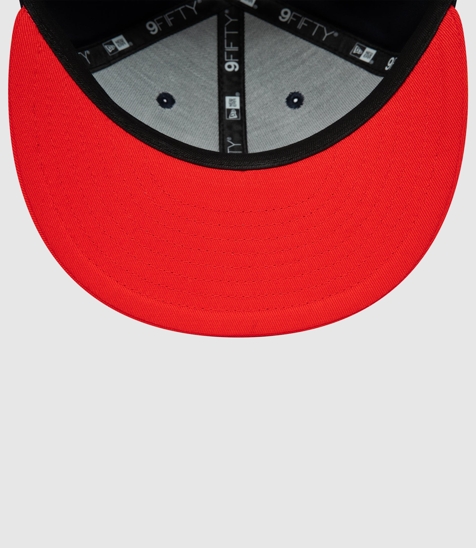 Close up of red brim on navy cap showing interior 9FIFTY branding