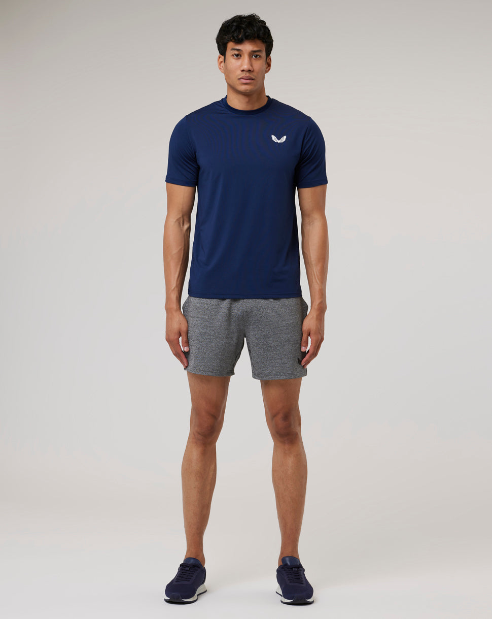 Full-body view of a man wearing a navy Peacoat Active 365 Tee with gray shorts and navy sneakers